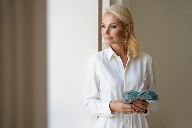 Free photo portrait of middle-aged blonde rich woman with cash money