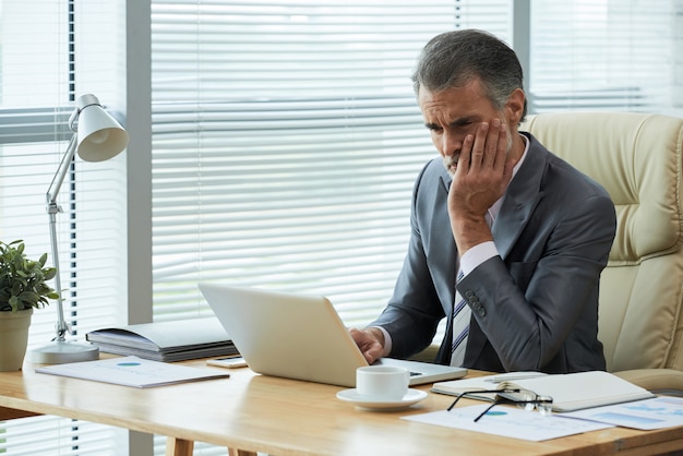 Portrait of middle-aged entrepreneur finding out about bankrupcy with frustrated gesture