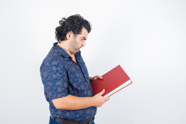 Portrait of middle aged man looking at book in shirt and looking thoughtful front view