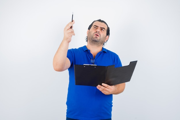 Portrait of middle aged man with clipboard while holding pencil in polo t-shirt