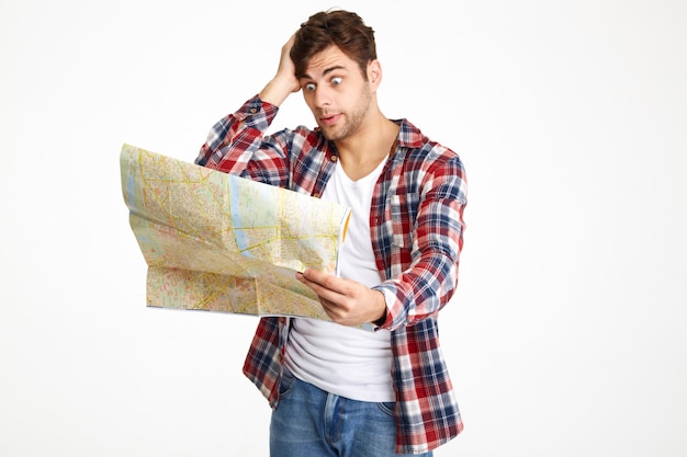 Портрет смешанного молодого человека, смотрящего на карту путешествия