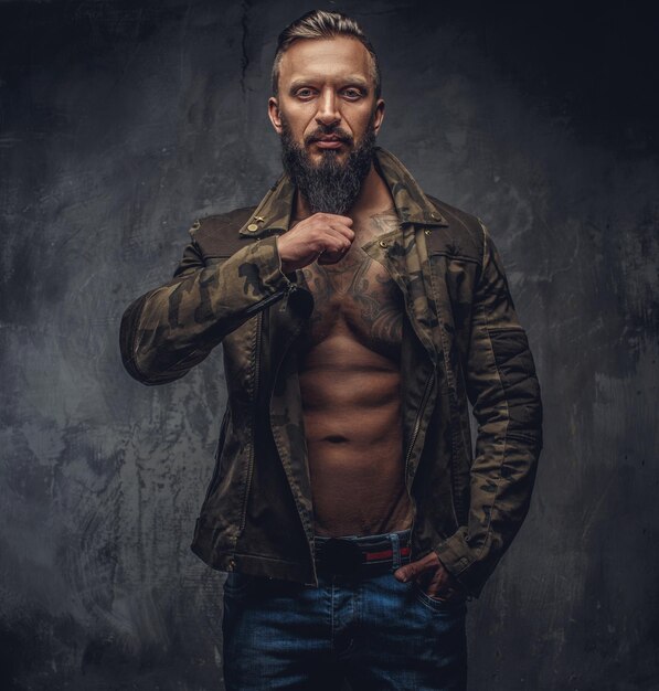 Portrait of modern bearded male in denim jeans and casual jacket dressed on naked torso.