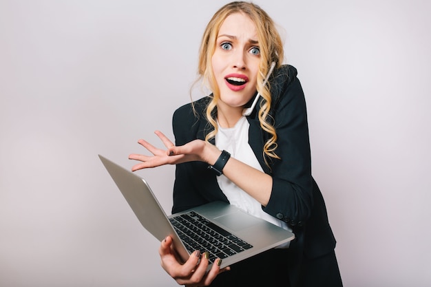 Portrait modern funny blonde office woman in white shirt and black jacket. Working with laptop, being busy, talking on phone, astonished, problems, expressing true emotions