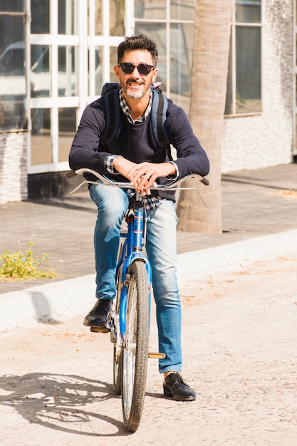 Portrait of modern man wearing black sunglasses sitting on bicycle