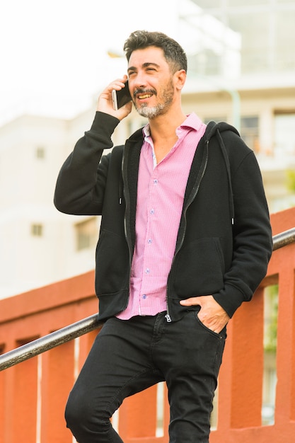 Portrait of modern man with his hand in pocket talking on mobile phone