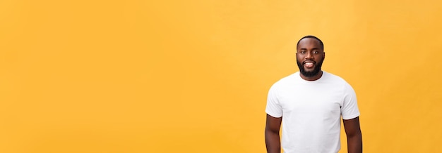 Portrait of a modern young black man smiling standing isolated yellow background