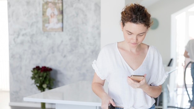 Foto gratuita ritratto della madre che controlla il suo telefono cellulare