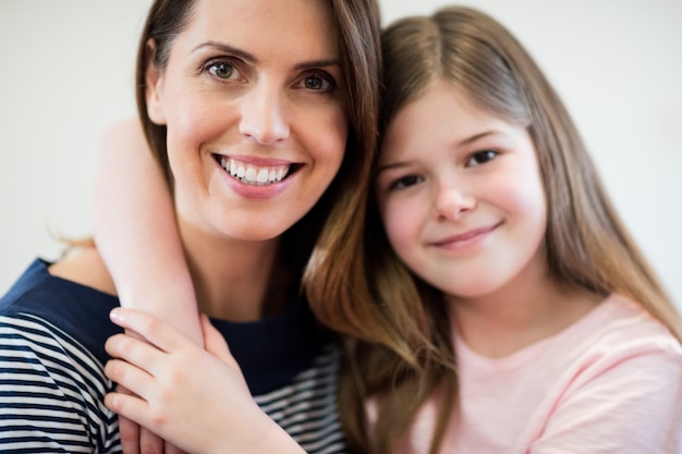 Portrait of mother and daughter embracing each other in living r