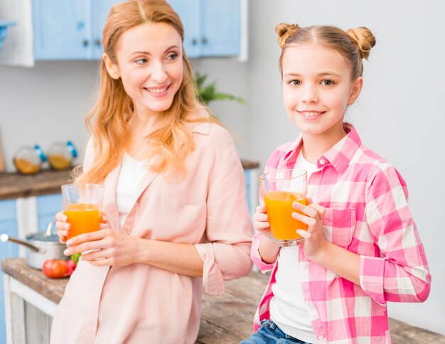 Portrait of mother and daughter holding glass of juice in hand