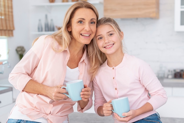 Portrait of mother and daughter holding mug