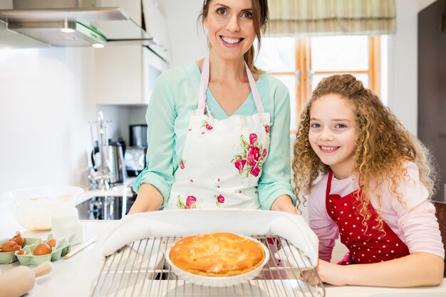 Portrait of mother and daughter holding pancake in cooling rack