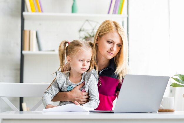 Free photo portrait of a mother and daughter working on laptop