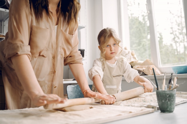 Portrait of mother and little girl shaping clay together