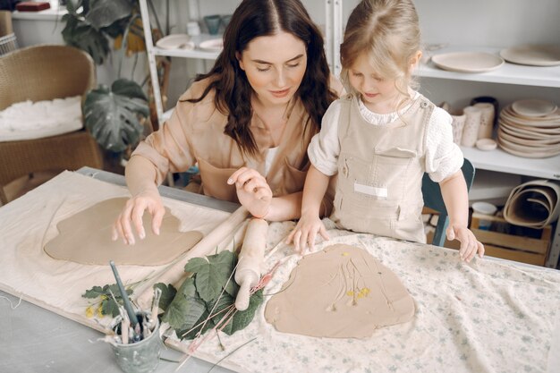 Portrait of mother and little girl shaping clay together