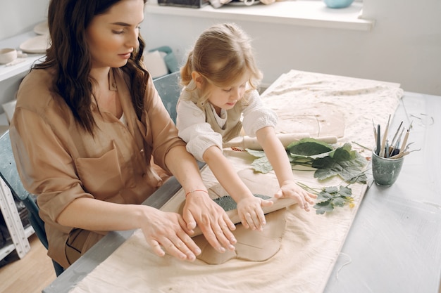 Portrait of mother and little girl shaping clay together