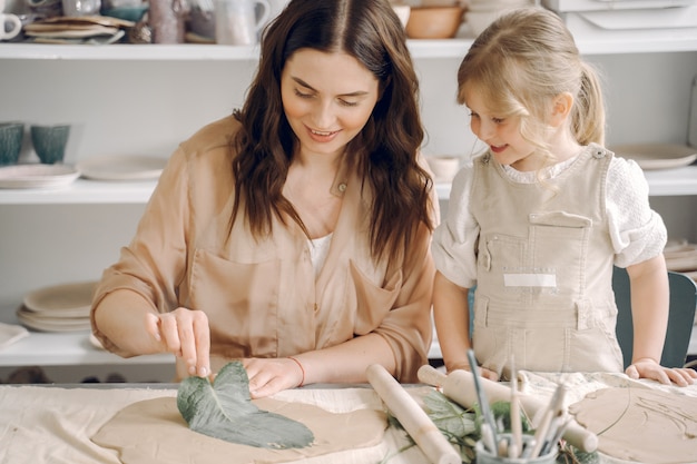 Portrait of mother and little girl shaping clay together