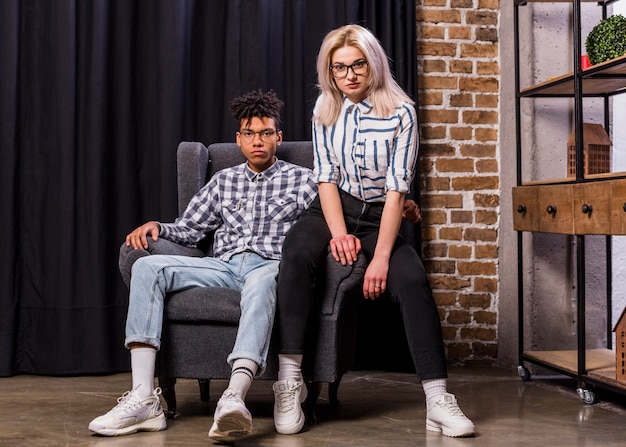 Portrait of multi ethnic couple sitting on armchair looking at camera