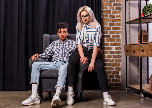 Portrait of multi ethnic couple sitting on armchair looking at camera