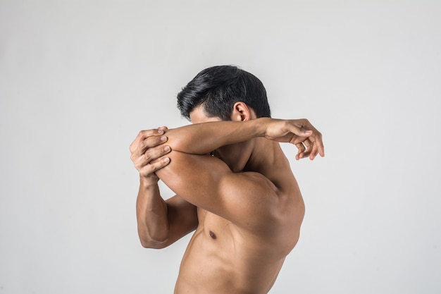 Portrait of a muscle man having elbow pain isolated on white background