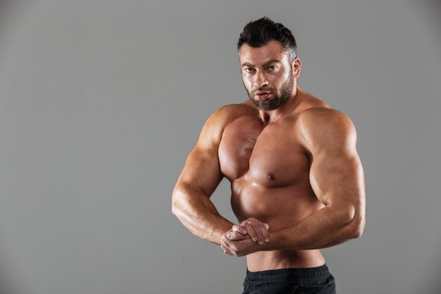 Портрет мускулистого уверенно без рубашки мужского культуриста