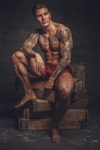 Portrait of naked muscular guy with tattooes on his body.