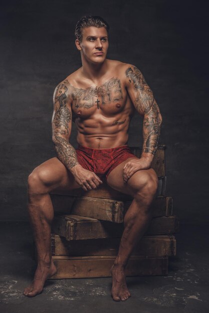 Portrait of naked muscular guy with tattooes on his body.