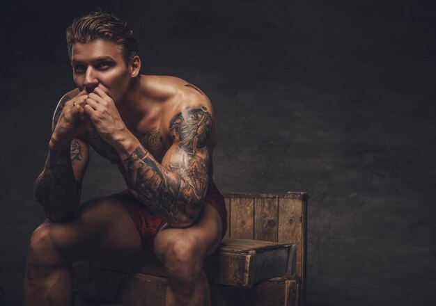 Portrait of naked muscular guy with tattooes on his body.
