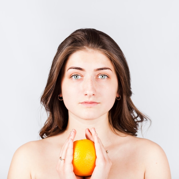 Portrait of naked woman holding orange