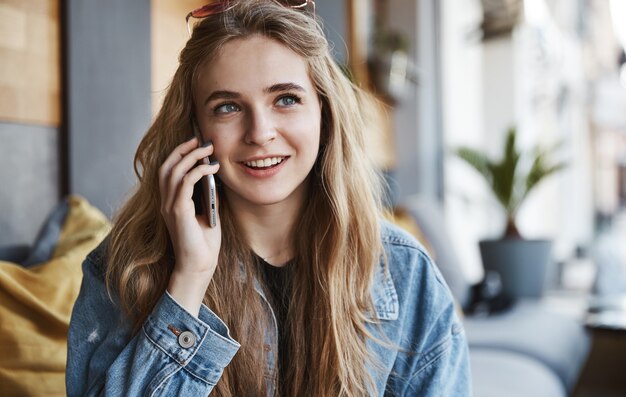 Portrait of natural girl sitting in cafe outdoors and talking on