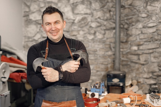 Free photo portrait of a nature craftsman looking in camera and posing for a photo man wearing an apron grounge dark stone texture background