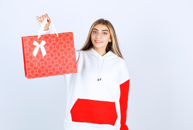 Portrait of nice woman model standing and showing gift bag