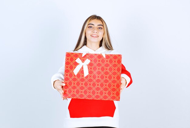 Portrait of nice woman model standing and showing gift bag