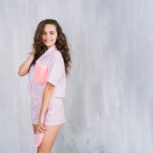 Portrait o a smiling young woman standing in front of wall