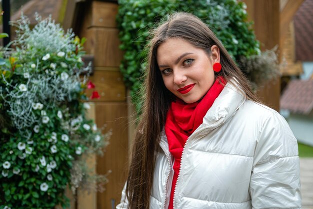 Портрет красивой молодой девушки в легкой куртке с красным шарфом на шее