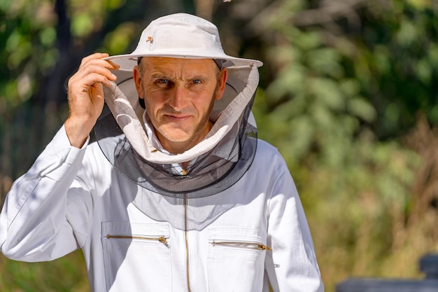 Портрет пчеловода в защитной шляпе с сеткой. серьезный работник пасеки. мужчина смотрит в камеру. крупный план.