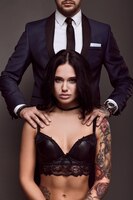 Бесплатное фото Портрет бизнесмена в элегантном костюме позирует с сексуальной женщиной с татуировкой в нижнем белье