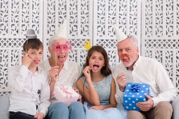 Бесплатное фото Портрет семьи, держащей реквизит и подарочные коробки, торчащие язык