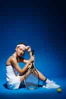 無料写真 ラケットとボールが床に座っている女性のテニスプレーヤーの肖像画