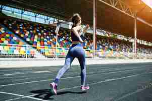 Бесплатное фото Портрет сильной девушки в спортивной одежде, бегущей по стадиону