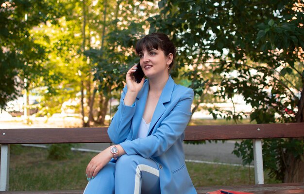 세련 된 옷을 입고 사무실 근처 휴대 전화를 호출 하는 세련 된 웃는 비즈니스 여자의 초상화. 여성의 비즈니스 스타일.