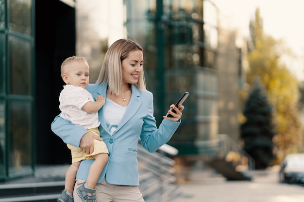 Бесплатное фото Портрет успешной бизнес-леди в голубом костюме с ребенком