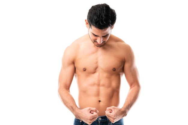 Бесплатное фото Портрет молодого человека в возрасте 20 лет, сгибающего мышцы тела на белом фоне