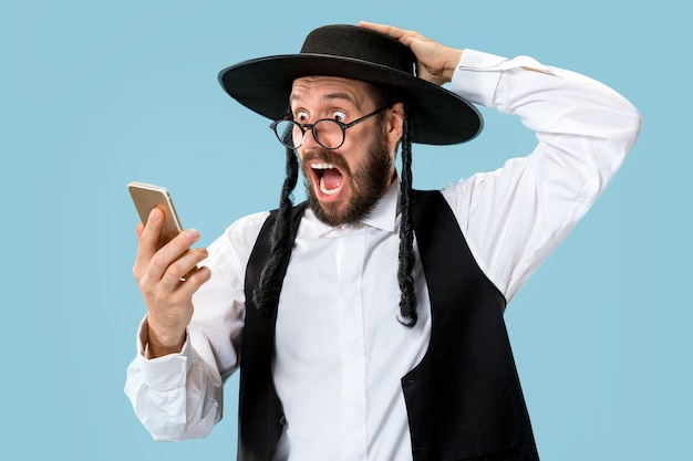 Портрет молодого ортодоксального еврея с мобильным телефоном на