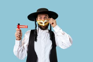 Портрет молодого ортодоксального еврея с деревянной трещоткой во время фестиваля пурим