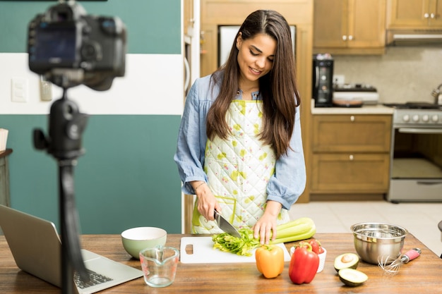 Бесплатное фото Портрет молодой женщины, готовящей еду для своего видеоблога дома