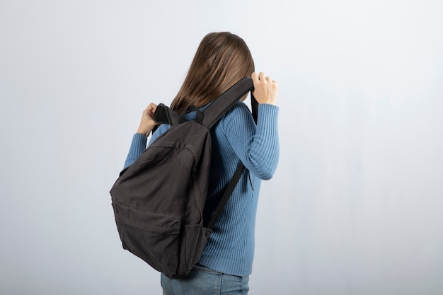 Бесплатное фото Портрет молодой женщины модели стоя с рюкзаком и позирует.