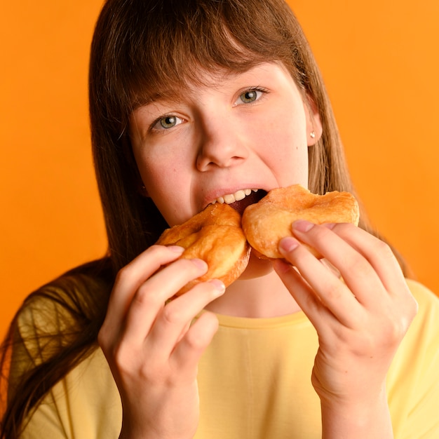 Бесплатное фото Портрет очаровательны молодая девушка ест пончики