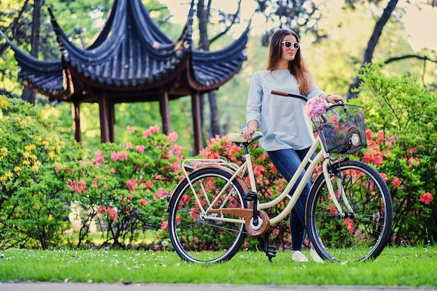 無料写真 公園の伝統的な中国のパビリオンの近くにシティ自転車で魅力的な女性の肖像画。