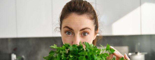 無料写真 新鮮なハーブや野菜を料理してパセリの束を持つ魅力的な女の子の肖像画