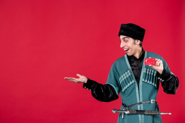 Бесплатное фото Портрет азербайджанского мужчины в традиционном костюме, держащего кредитную карту на красных деньгах, весенний цвет, этнический новруз